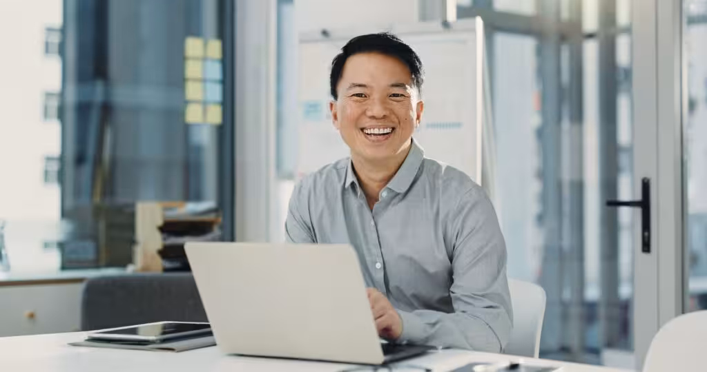 man-smiling-using-laptop-office