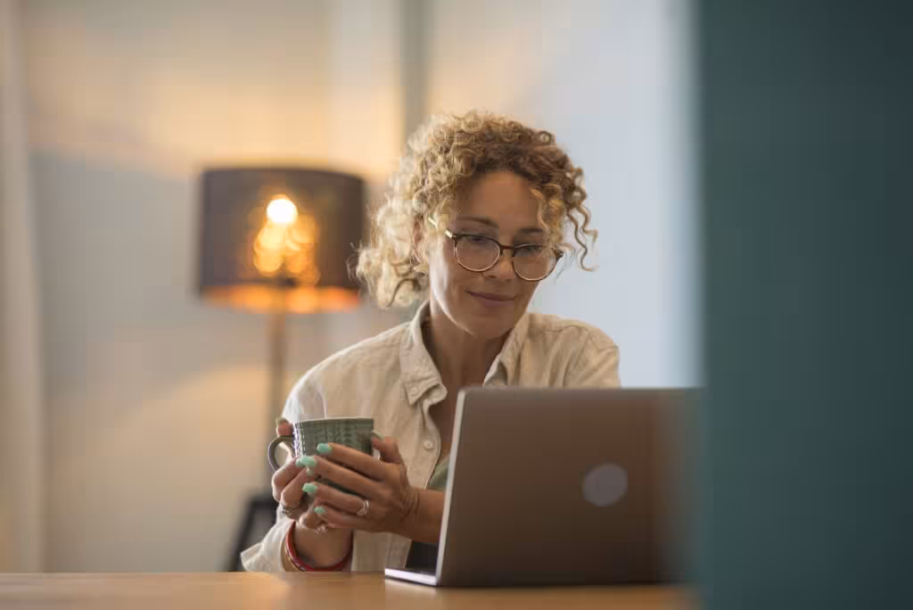woman-smiling-holding-coffee-and-laptop